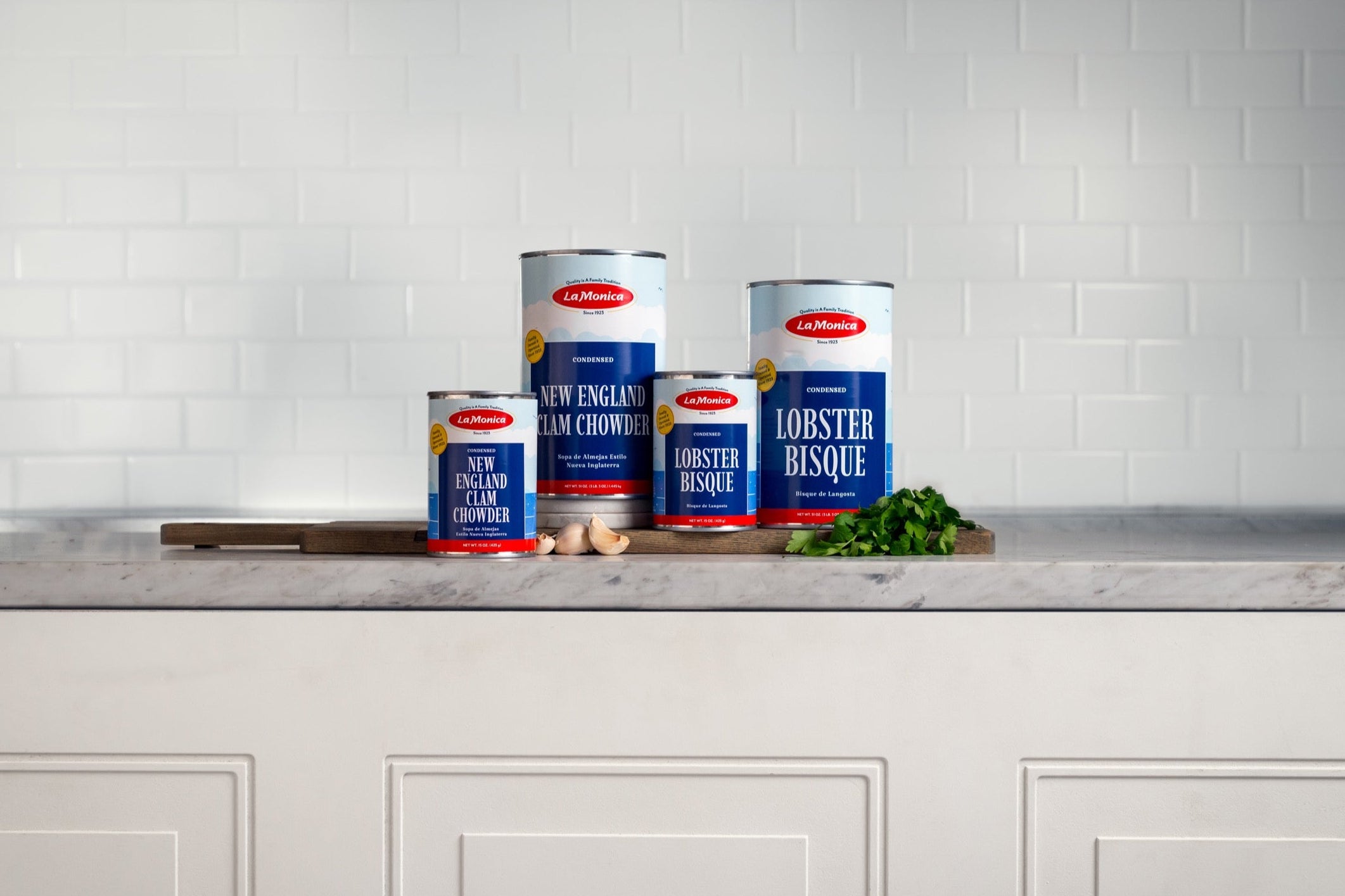 Four cans of soup on a kitchen counter with a tiled wall background.