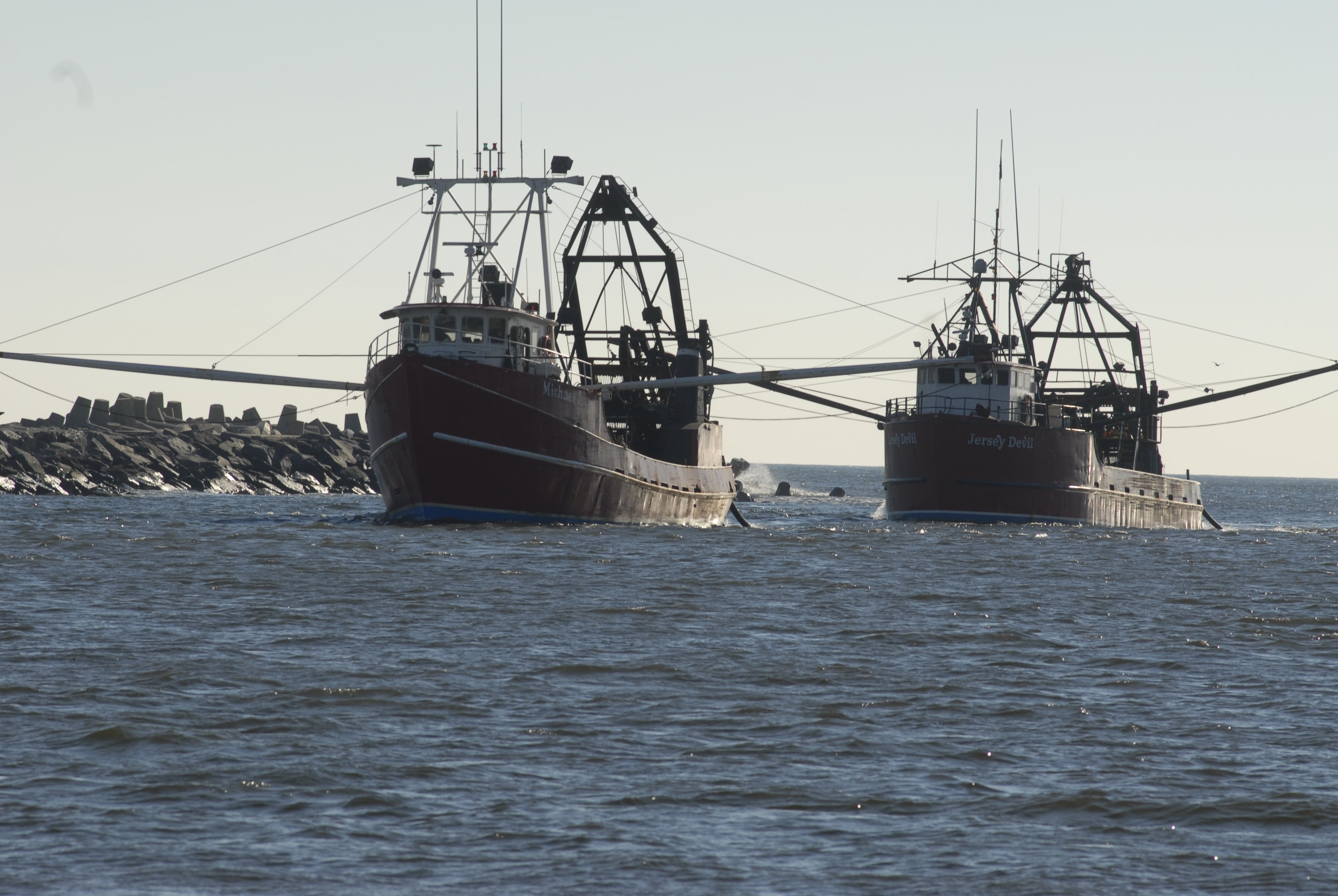 Two fishing boats in the water with a clear sky background