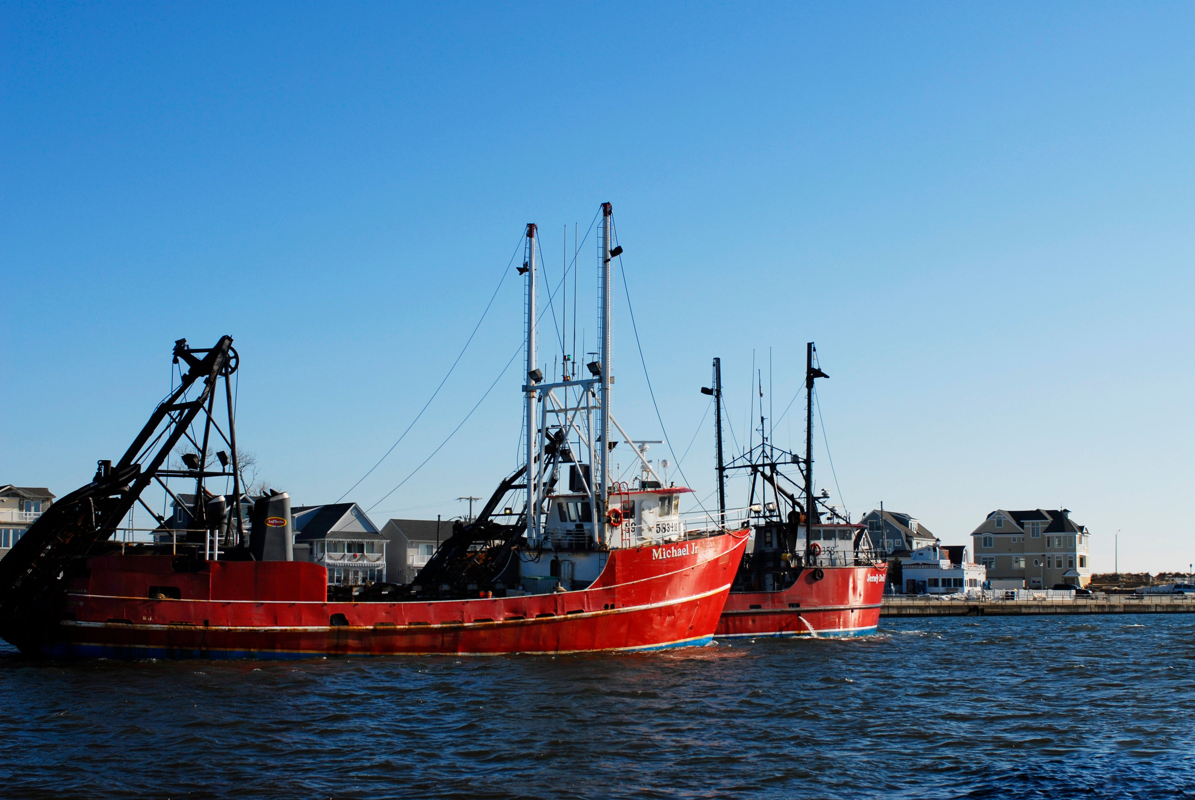 Red fishing boat in a harbor with clear blue sky